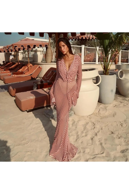 Miraee Paris Luna striped long-sleeve beach cover-up dress in a fitted silhouette worn on a sandy beach.