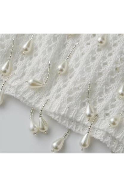 Miraee Paris white crochet cover-up featuring delicate hanging pearl-like teardrop embellishments on a knit fabric.